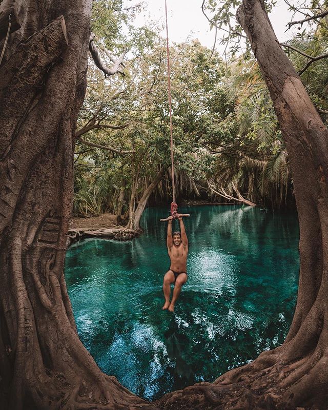 Man swinging on rope swing above Mosh Hot Spring