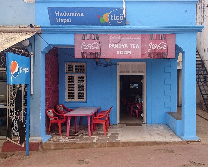 Blue building with red plastic cola table and chairs out front.